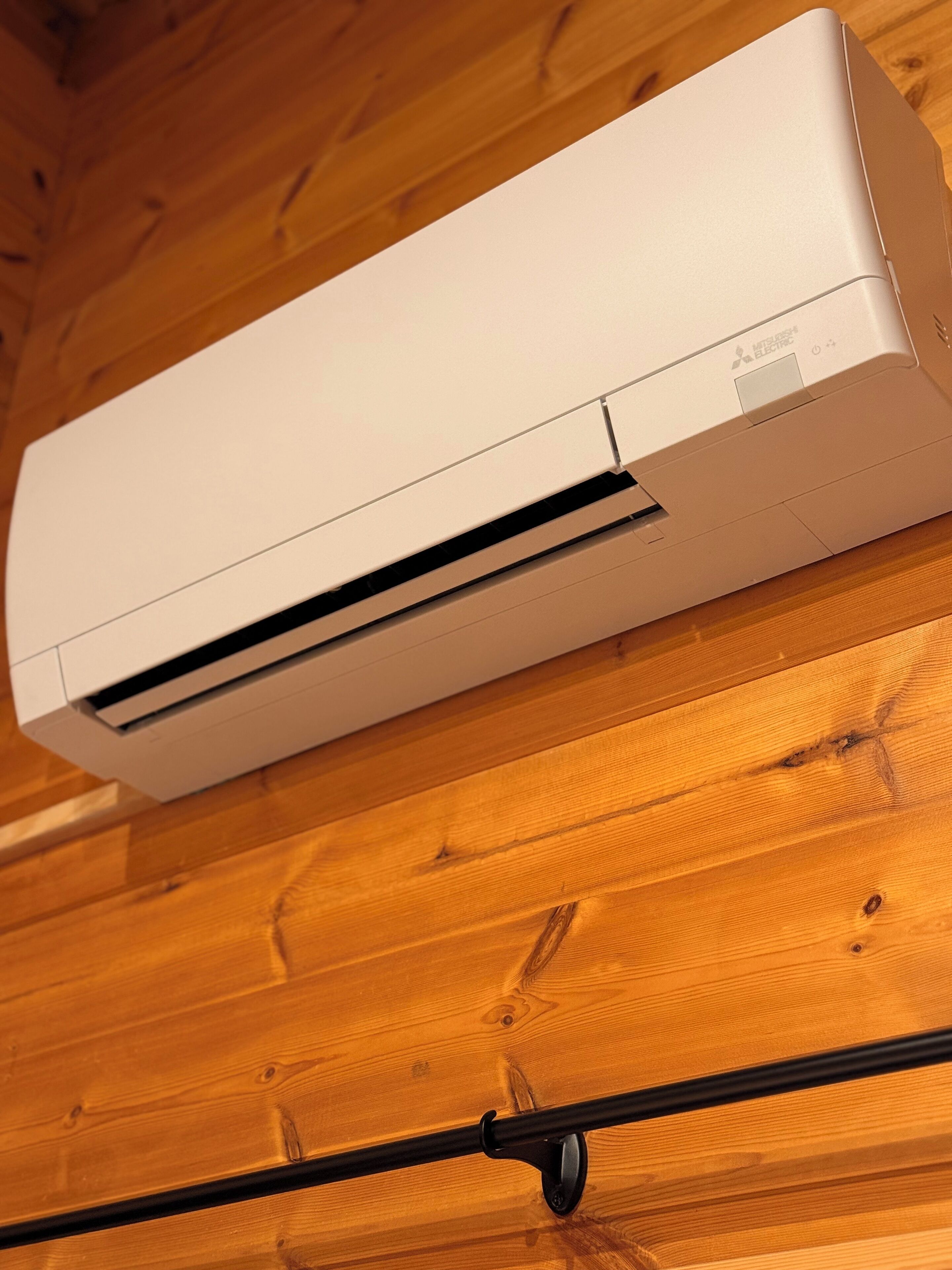 A white air conditioning unit mounted on a wooden wall.