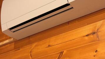 A white air conditioning unit mounted on a wooden wall.
