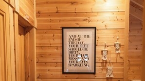A wooden-paneled room with a framed motivational quote, a small heater, and a macrame wall hanging. - Sohana Chalet (Kappel-Grafenhausen)