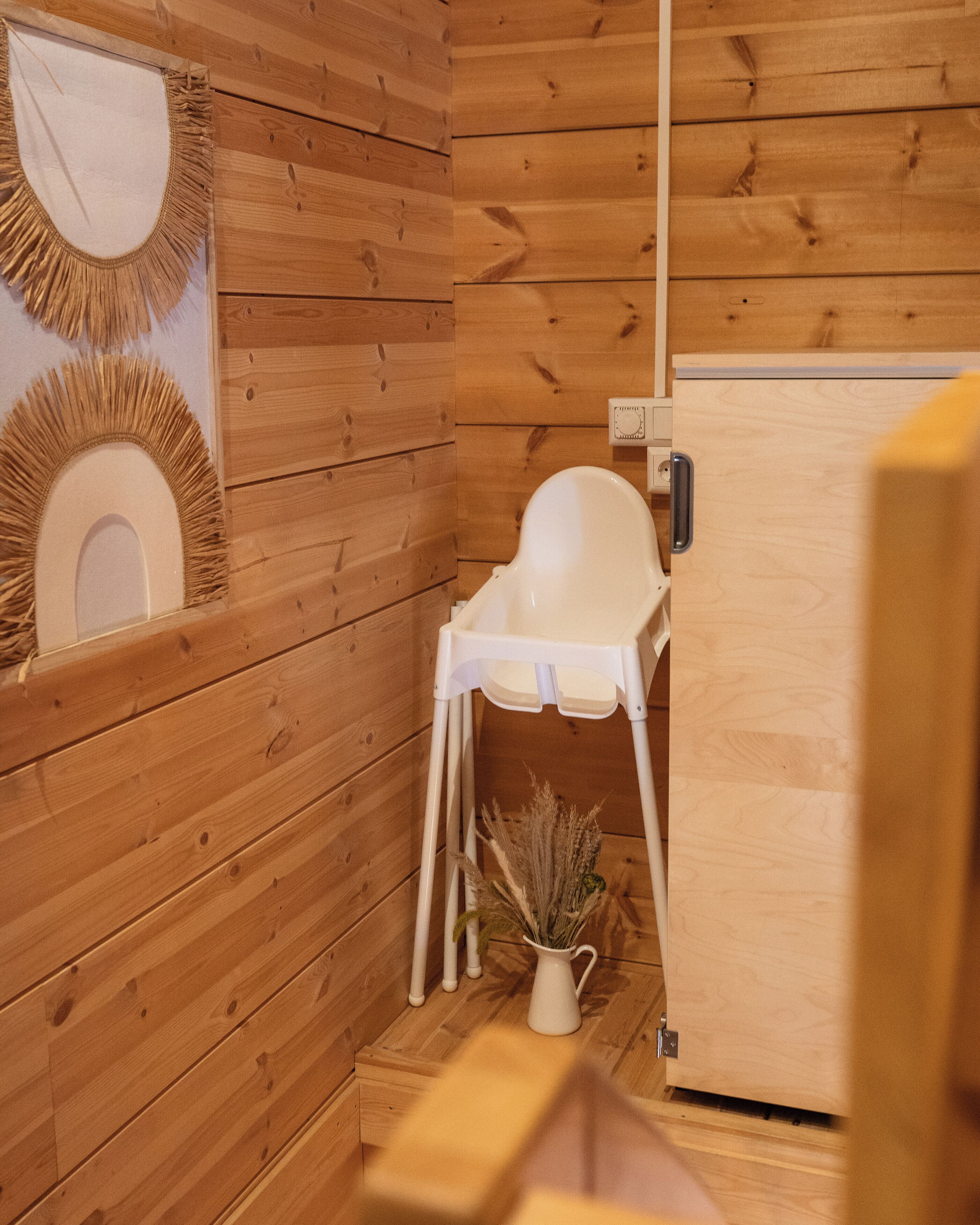 Ein Holzblockhaus-Innenraum mit einem weißen Stuhl, einem kleinen Tisch und einem weißen Schrank.