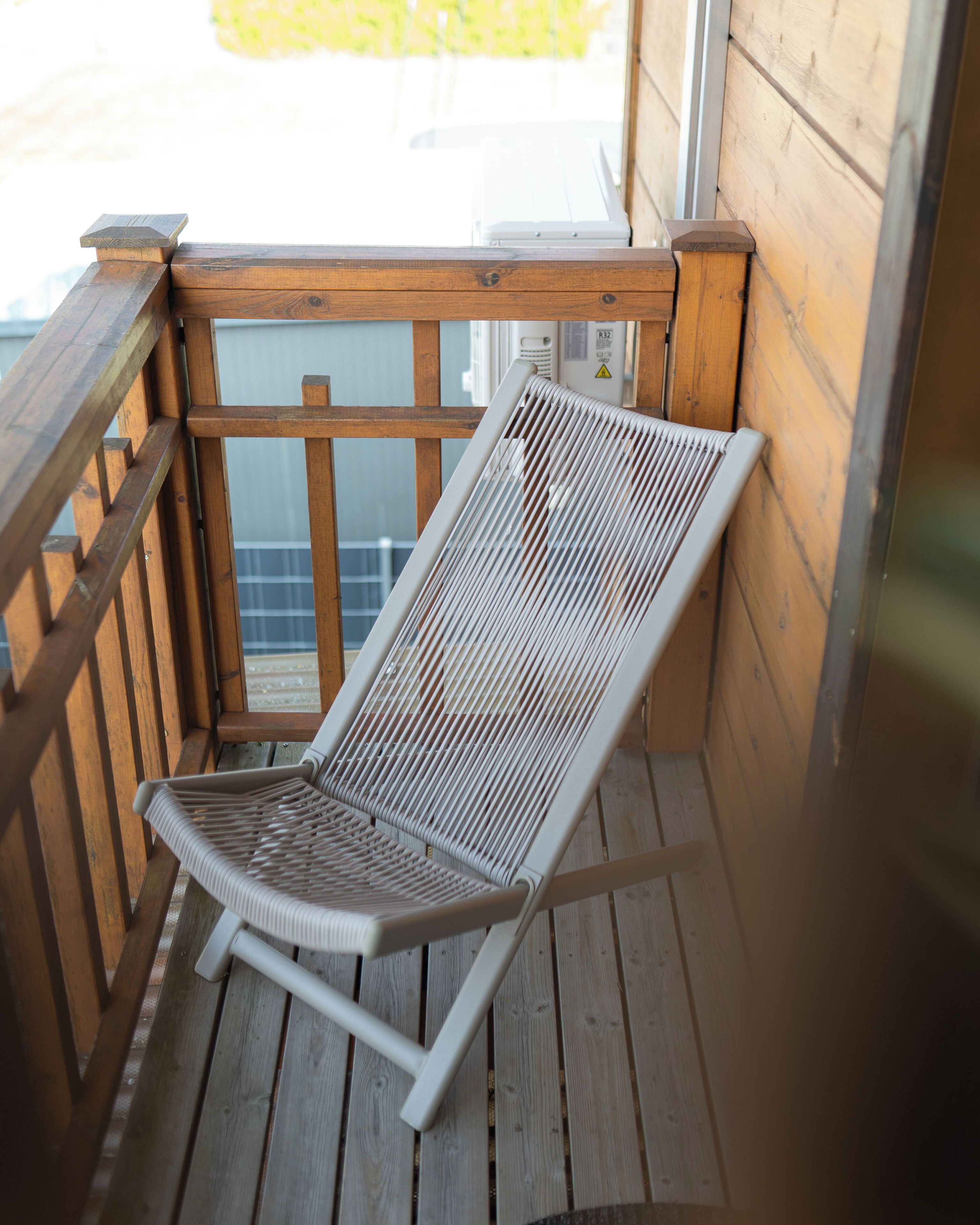Une terrasse en bois avec un fauteuil de relaxation à structure métallique.