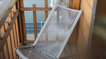 Une terrasse en bois avec un fauteuil de relaxation à structure métallique.