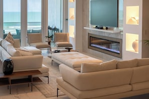 Ein modernes Wohnzimmer mit einer Couch, Sesseln, einem Couchtisch und einem Kamin.
