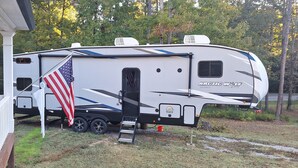 A recreational vehicle (RV) with a covered porch and an American flag. - 2-bedroom recreational vehicle in enchanting Cartersville with AC (Cartersville)