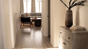 En moderne stue med en sofa, en lænestol, et lille bord og en dekorativ vase på et skab.