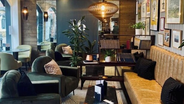 A modern lounge area with a sofa, armchairs, a coffee table, and a bookshelf. - Beds at 46 (Cowes)