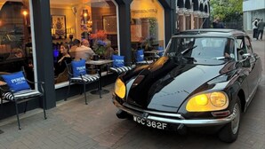 A black car parked in front of a building with arched windows and a sign that reads "PERON." - Beds at 46 (Cowes)