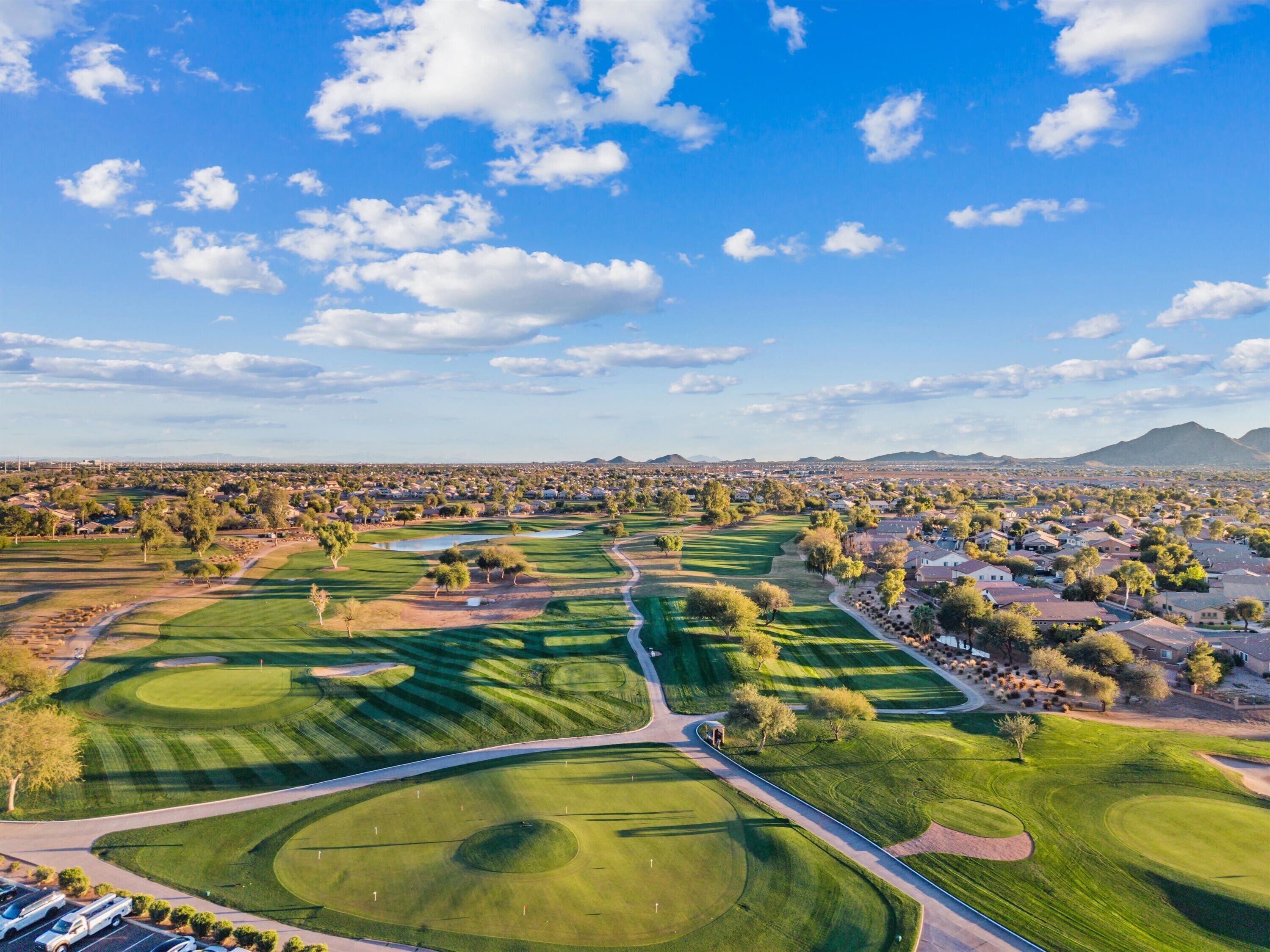 A golf course with multiple greens and fairways, surrounded by residential areas and a mountain in the background.