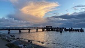 Un muelle se adentra en aguas tranquilas con un atardecer de fondo.