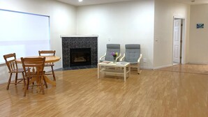 Una habitación amplia con chimenea, muebles de madera y una puerta que da a otra zona.