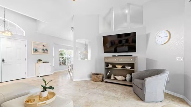 A modern living room with a flat-screen TV, a grey sofa, and a white coffee table with a tray and plant. - Stylish Private Heated Pool, close to beach (Port Charlotte)