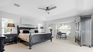 A bedroom with a bed, bedside tables, a desk, a chair, a wardrobe, and a ceiling fan. - Stylish Private Heated Pool, close to beach (Port Charlotte)