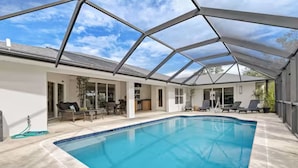 A covered swimming pool with a glass ceiling, a patio area with seating, and a view of the sky. - Stylish Private Heated Pool, close to beach (Port Charlotte)