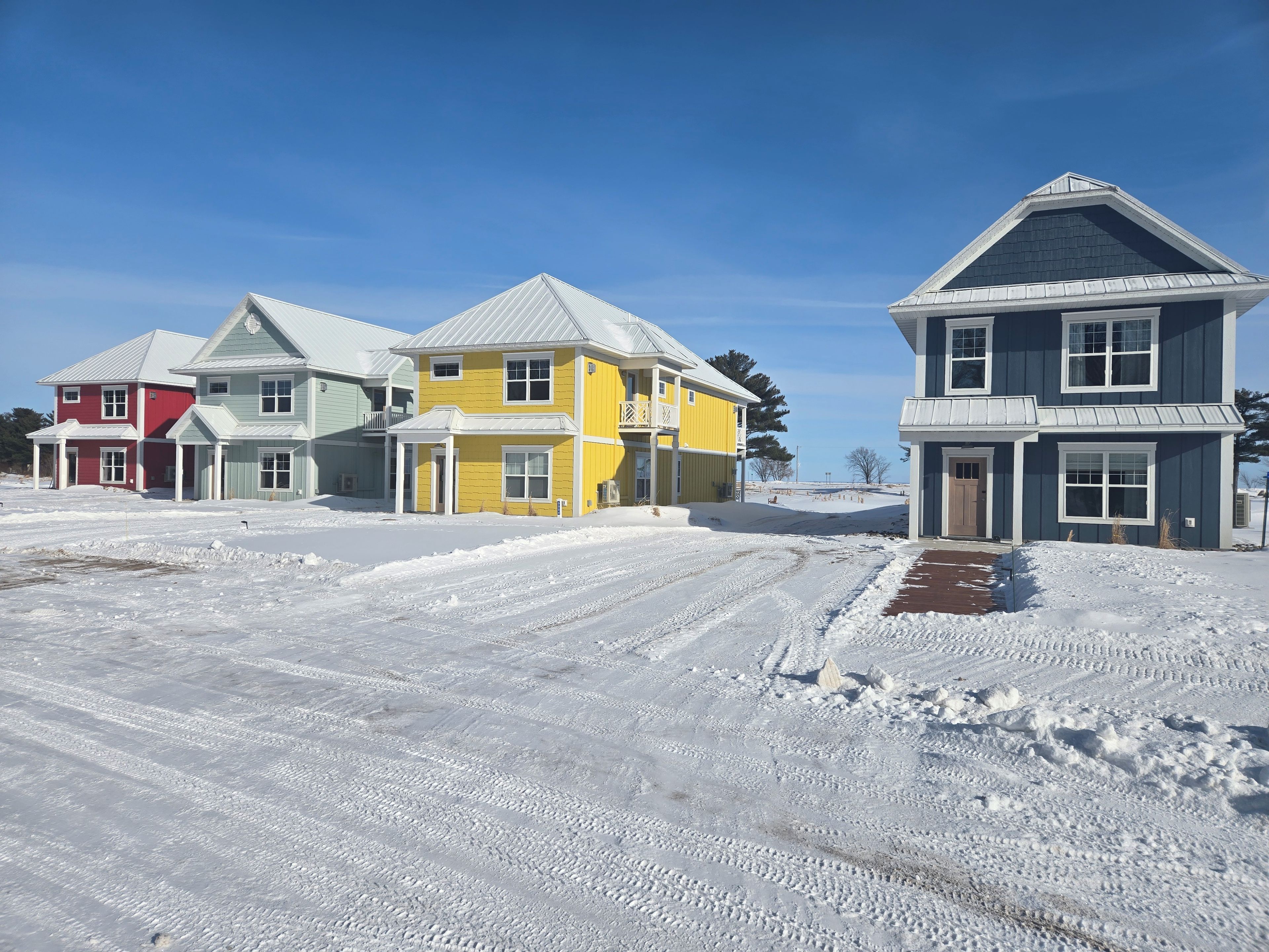 A residential area with houses, a clear sky, and snow-covered ground.