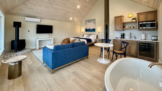 Un interior moderno con techo estilo loft, un sofá grande, una mesa de comedor, una zona de cocina y una bañera.