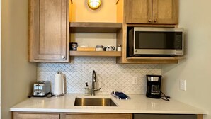 Una cocina con armarios de madera, un microondas de acero inoxidable, una cafetera y un tostador.