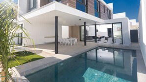 Et moderne hus med to etager, swimmingpool, udendørs spiseplads og havudsigt.