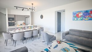 A modern living room with a dining area, grey sofas, a marble floor, and a colorful abstract painting. - Protaras Aqua Pearl Villa AQ12 by Interhome (Protaras)