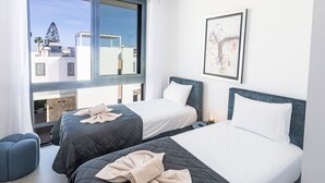Hotellihuone, jossa on kaksi sänkyä, suuri ikkuna ja näkymä kaupunkiin.