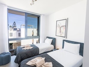 Ein Hotelzimmer mit zwei Betten, einem großen Fenster und Blick auf die Stadt.