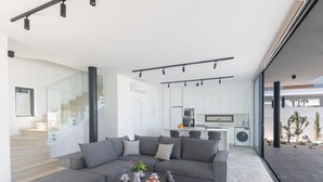 A modern living room with a sectional sofa, a coffee table, and a kitchen in the background. - Protaras Aqua Pearl Villa AQ05 by Interhome (Protaras)