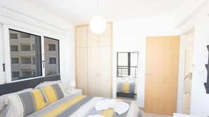Una habitación de hotel con cama, armario, escritorio y ventana.