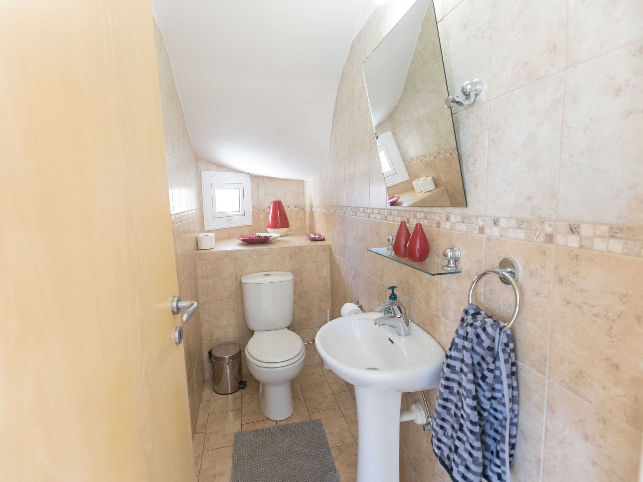 A bathroom with a toilet, sink, and mirror.