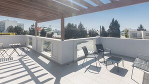 A rooftop terrace with a wooden pergola, white walls, and a view of the cityscape. - Ayia Napa Satin Villa SVI3 by Interhome (Ayia Napa)