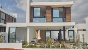 Een modern huis met twee verdiepingen, grote ramen, een balkon en een zwembad.
