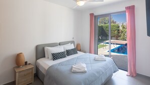A bedroom with a bed, a nightstand, a ceiling fan, and a view of an outdoor swimming pool. - Ayia Napa Satin Villa SVI1 by Interhome (Ayia Napa)