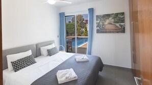 A bedroom with a bed, a ceiling fan, a painting, and a view of an outdoor swimming pool. - Ayia Napa Satin Villa SVI1 by Interhome (Ayia Napa)