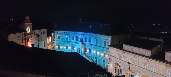 A historic building with a clock tower, illuminated windows, and a prominent entrance. - Panoramic apartment in the heart of Fermo (Fermo)