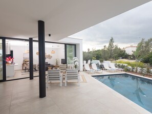 A modern outdoor living space with a pool, lounge chairs, and a dining area. - Protaras Aqua Pearl Villa AQ01 by Interhome (Protaras)