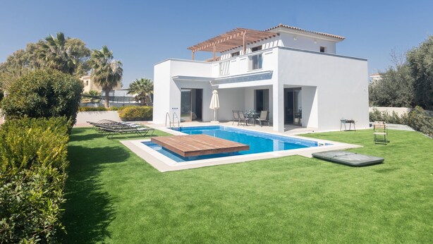 Een modern huis met twee verdiepingen, een zwembad, terras en een verzorgd gazon.