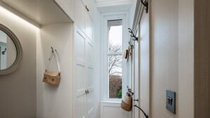 A hallway with white doors, a bench, a basket, and a window with a view of trees. - Viktorianische Villa mit Strandblick by Interhome (Dundee)