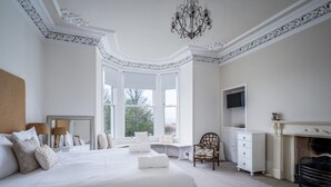 A spacious bedroom with a large bed, a fireplace, a television, and a view through the window. - Viktorianische Villa mit Strandblick by Interhome (Dundee)