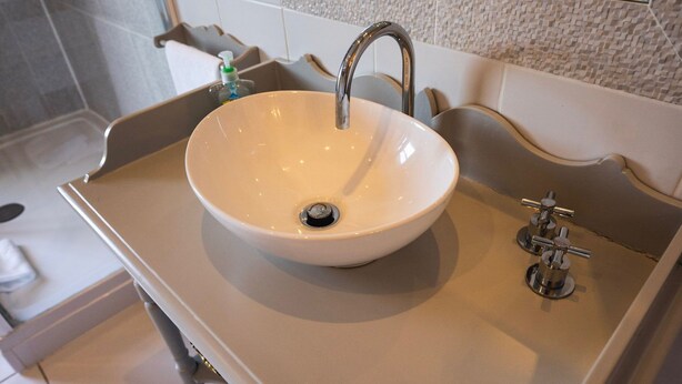 A bathroom with a white sink, a modern faucet, and a mirror above it. - Viktorianische Villa mit Strandblick by Interhome (Dundee)