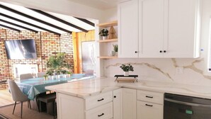 A modern kitchen with white cabinets, a marble countertop, and a built-in dishwasher. - Bright beach-city home — newly renovated. Only 3 mi. from SoCal beaches!   (Torrance)