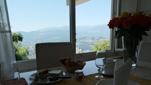 Uma mesa de jantar com vista para montanhas e uma cidade.