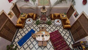 Un riad marocain doté d’une cour intérieure, de meubles en bois richement décorés et de carreaux aux motifs variés.