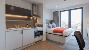 A modern hotel room with a kitchenette, a bed with a view, and a large window. - Student Only True Glasgow (Glasgow)