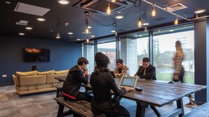 A modern meeting room with a wooden table, comfortable seating, and large windows offering a view of the outside. - Student Only True Glasgow (Glasgow)