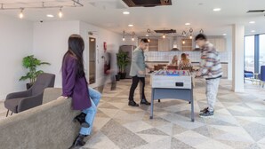 A modern indoor space with a foosball table, seating areas, and a kitchen in the background. - Student Only True Glasgow (Glasgow)