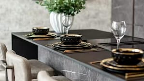 A modern dining area with a marble table, black and gold dinnerware, and a potted plant. - Near Transport - Hot tub - Fireplace - Sleeps 2 (Edinburgh)