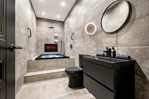 A modern bathroom with a black vanity, a round mirror, a built-in shower, and a Netflix sign on the wall. - Near Transport - Hot tub - Fireplace - Sleeps 2 (Edinburgh)