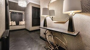 A hallway with a dark wood floor, a chandelier, a mirror with two lamps, and a radiator. - Near Transport - Hot tub - Fireplace - Sleeps 2 (Edinburgh)