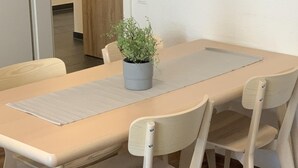Een eettafel met vier stoelen, een potplant en een lichtgekleurde tafelkleed.