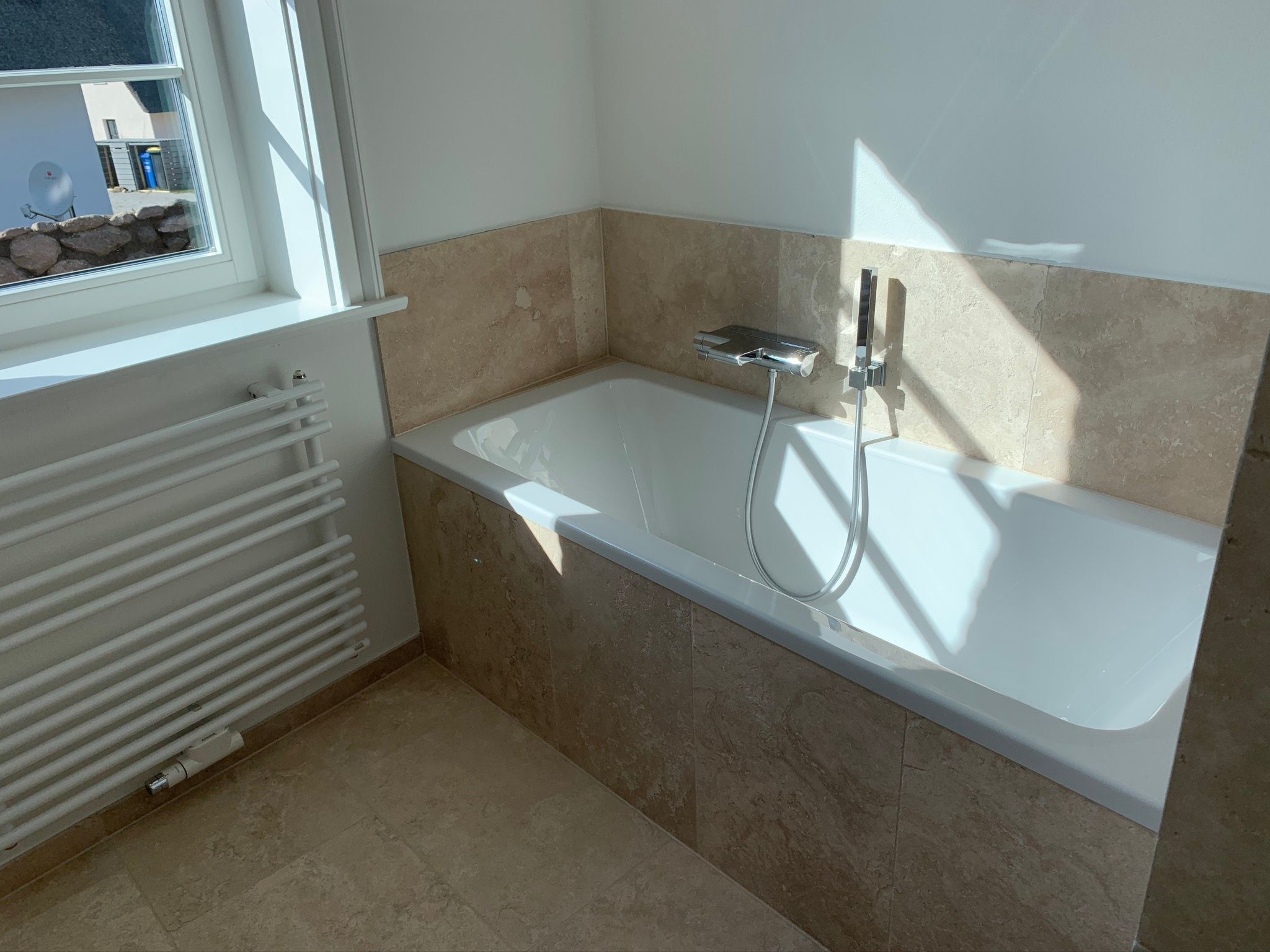 A bathroom with a bathtub, a window, and a radiator.