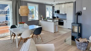 Et moderne køkken med hvide skabe, en central ø og en brændeovn.