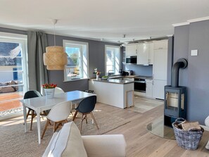 A modern kitchen with white cabinets, a central island, and a wood-burning stove. - Reethus Linda am Schloß Groß Schwansee by Interhome (Dassow)
